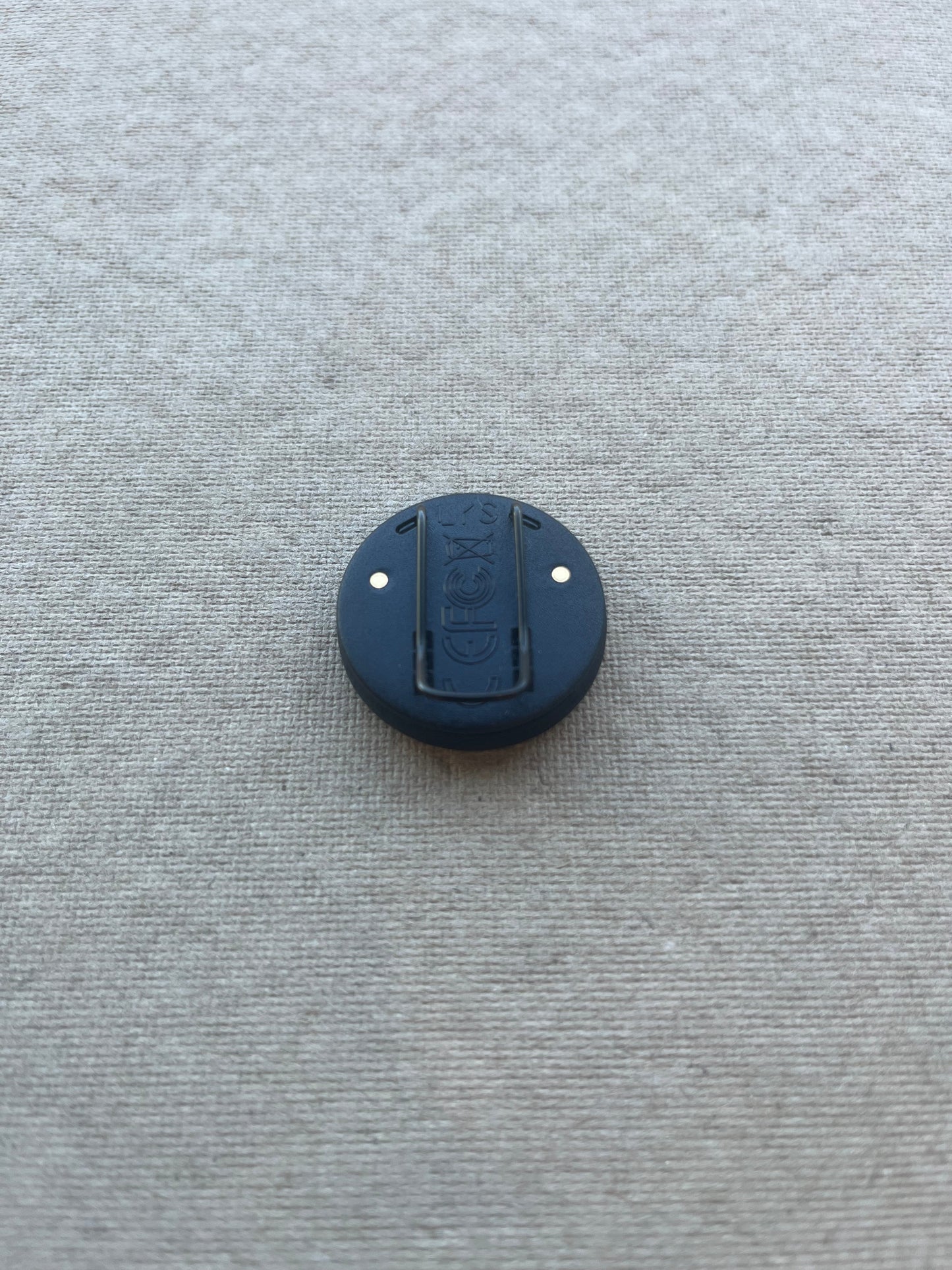 Back view of the LYS Button PRO, showing the clip with medical-grade coating and gold contact points for charging.