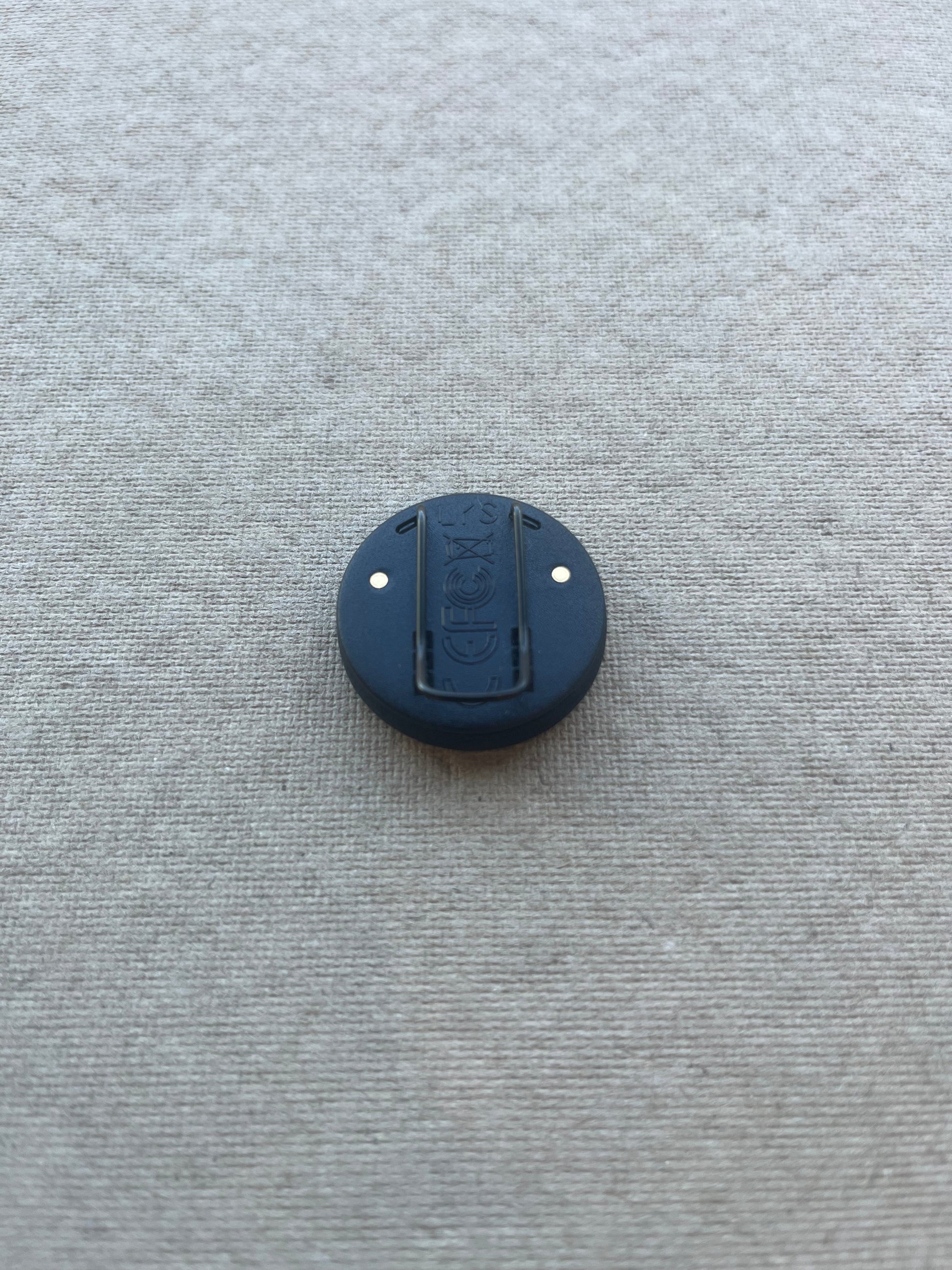 Back view of the LYS Button PRO, showing the clip with medical-grade coating and gold contact points for charging.